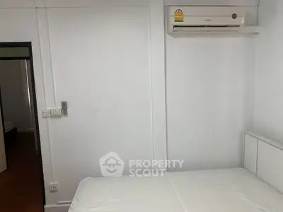 Minimalist bedroom with air conditioning and white walls, perfect for a cozy living space.