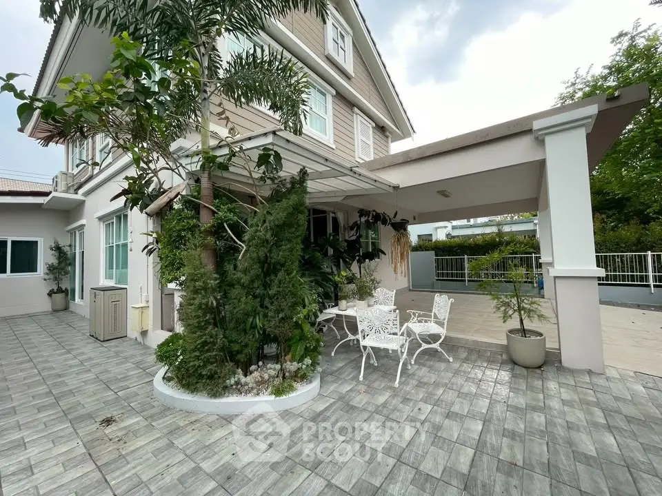 Charming two-story house with elegant patio and lush greenery, perfect for outdoor relaxation.