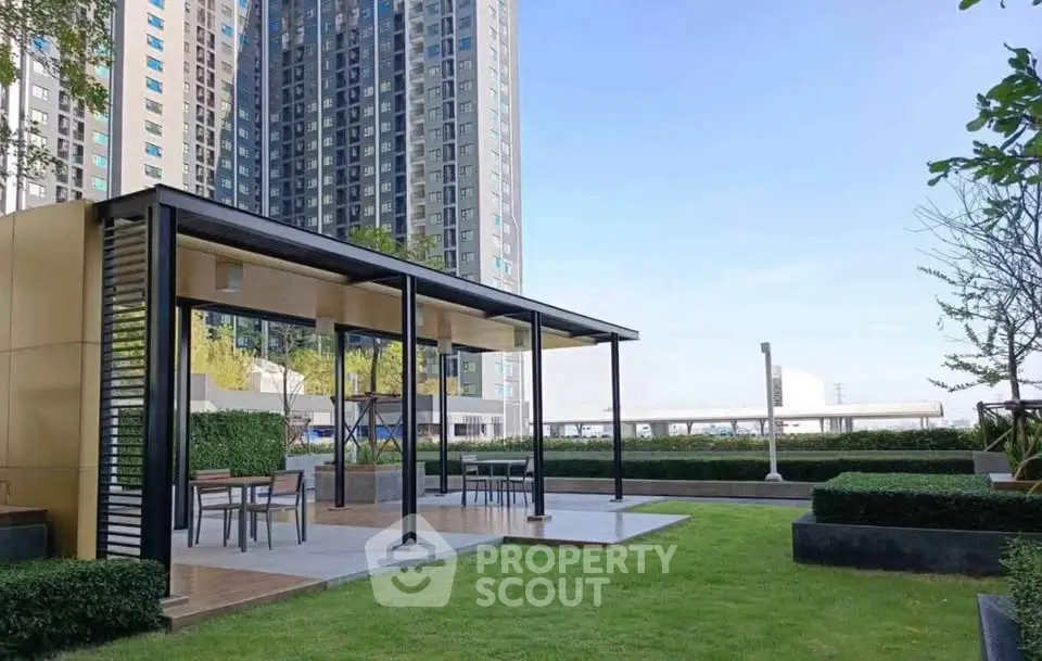 Modern outdoor seating area with lush greenery and high-rise building backdrop