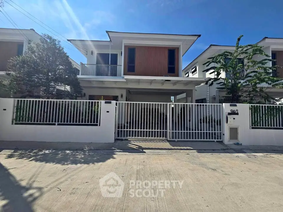 Modern two-story house with sleek design and gated entrance in a sunny neighborhood.