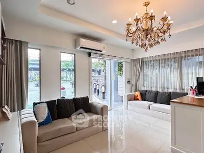 Elegant living room with chandelier and large windows offering natural light.