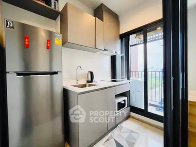 Modern kitchen with sleek cabinets and balcony view in urban apartment.