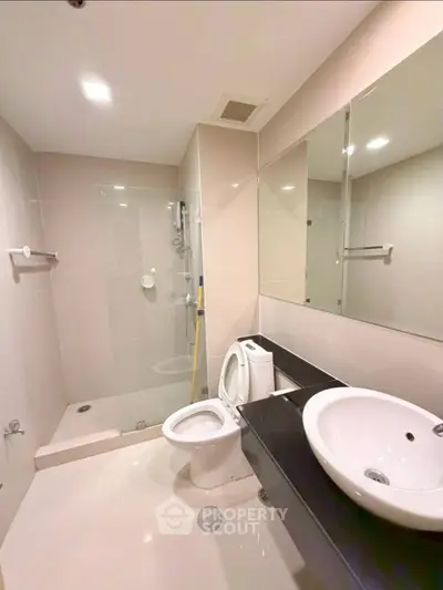 Modern bathroom with sleek fixtures and glass shower enclosure in a contemporary apartment.