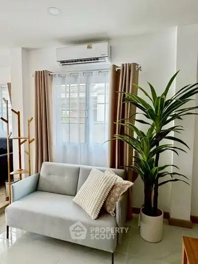 Cozy living room with modern sofa, air conditioning, and lush indoor plant.