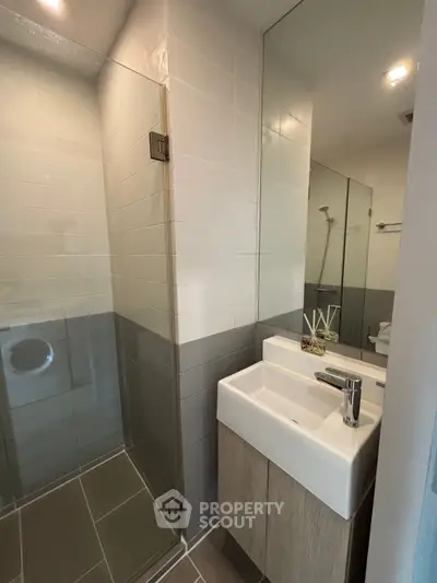 Modern bathroom with sleek glass shower and stylish sink in contemporary apartment.