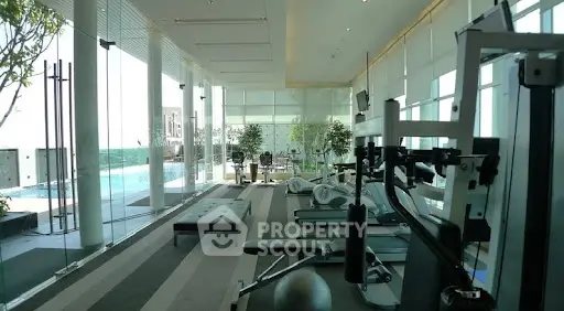 Luxurious gym with panoramic windows and pool view in modern high-rise building.