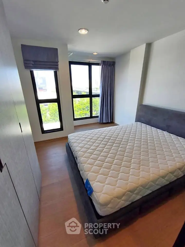 Modern bedroom with large window and stylish furnishings in a contemporary apartment.