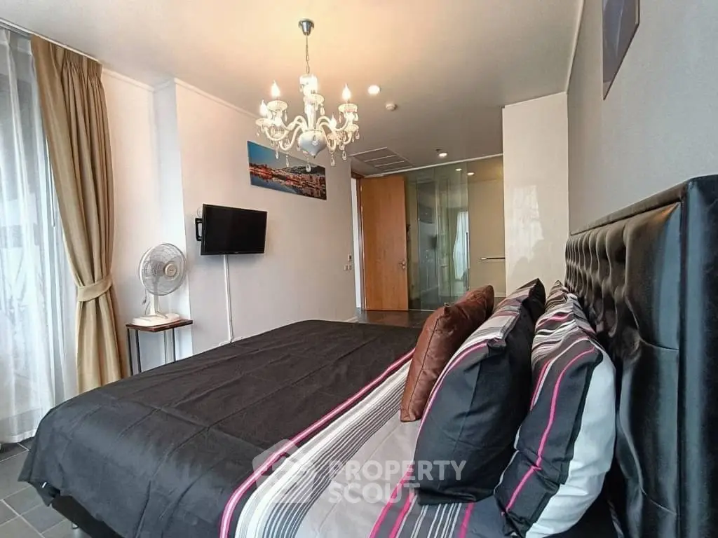 Luxurious bedroom with elegant chandelier and modern decor in a stylish apartment.