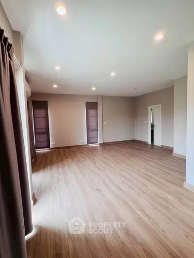 Spacious empty living room with wooden flooring and recessed lighting