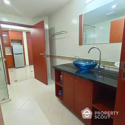 Modern bathroom with stylish basin and wooden cabinetry in a spacious apartment.