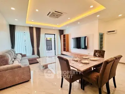 Spacious modern living room with elegant dining area and large TV, perfect for entertaining.