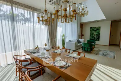 Luxurious dining and living area with elegant chandeliers and modern decor.
