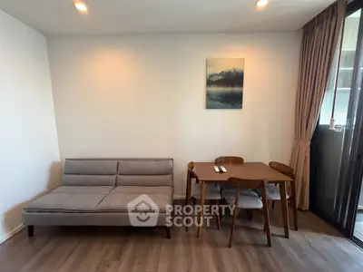 Modern living room with stylish sofa and dining set, featuring elegant wooden flooring and natural light.