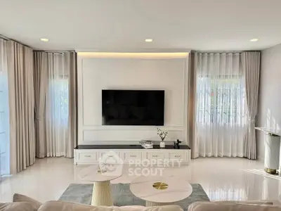 Elegant living room with modern decor and large TV, featuring soft lighting and stylish curtains.