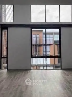 Spacious modern apartment with floor-to-ceiling windows offering a stunning urban view.