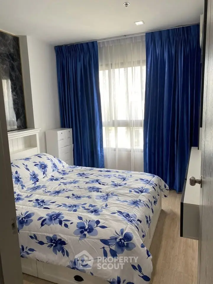Cozy bedroom with floral bedding and elegant blue curtains, perfect for relaxation and comfort.