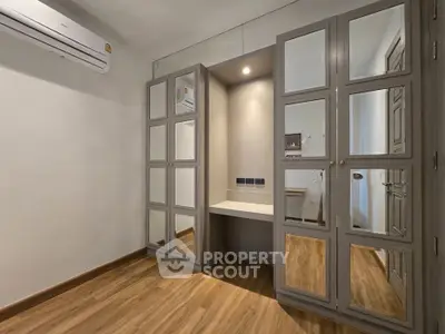 Spacious bedroom with mirrored wardrobes and wooden flooring, perfect for modern living.