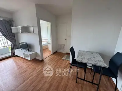 Modern apartment interior with open living area and dining space, featuring wood flooring and natural light.