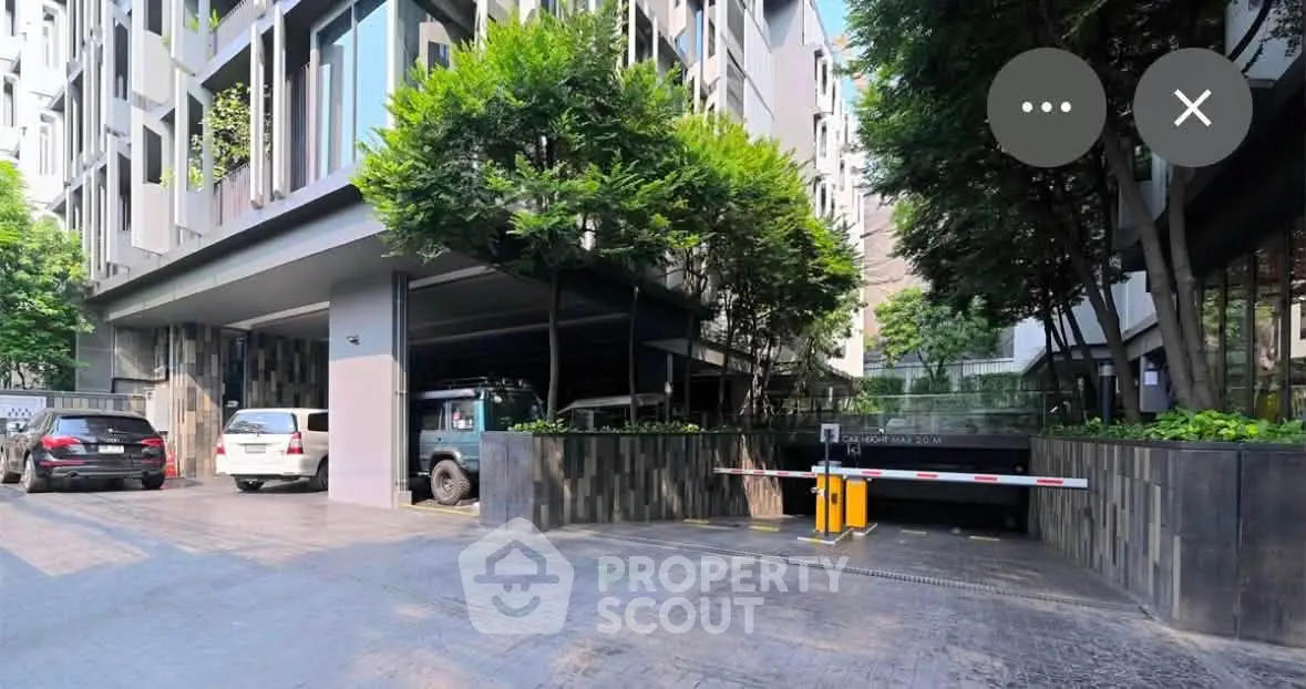 Modern building exterior with lush greenery and secure parking entrance.