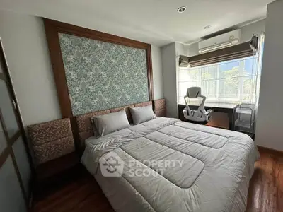 Spacious bedroom with elegant decor and large window offering natural light.