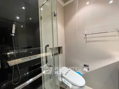 Modern bathroom with glass shower and sleek fixtures in luxury apartment.