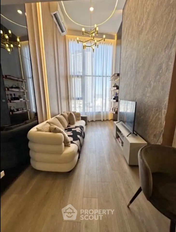 Luxurious modern living room with high ceilings, elegant chandelier, and floor-to-ceiling windows offering city views.
