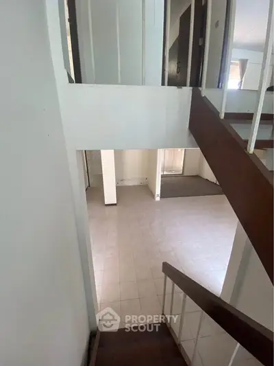 Spacious interior with tiled flooring and wooden staircase, ideal for modern living.