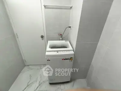Compact laundry room with modern washing machine and sleek tile flooring.