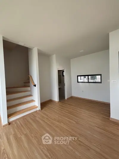 Spacious modern interior with wooden flooring and staircase, ideal for customization.
