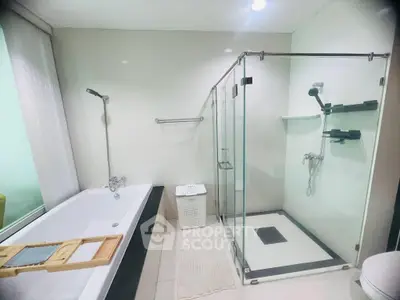 Modern bathroom with glass shower and bathtub in a sleek real estate property.