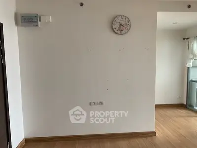 Minimalist interior with wooden flooring and wall clock, ideal for modern living space.
