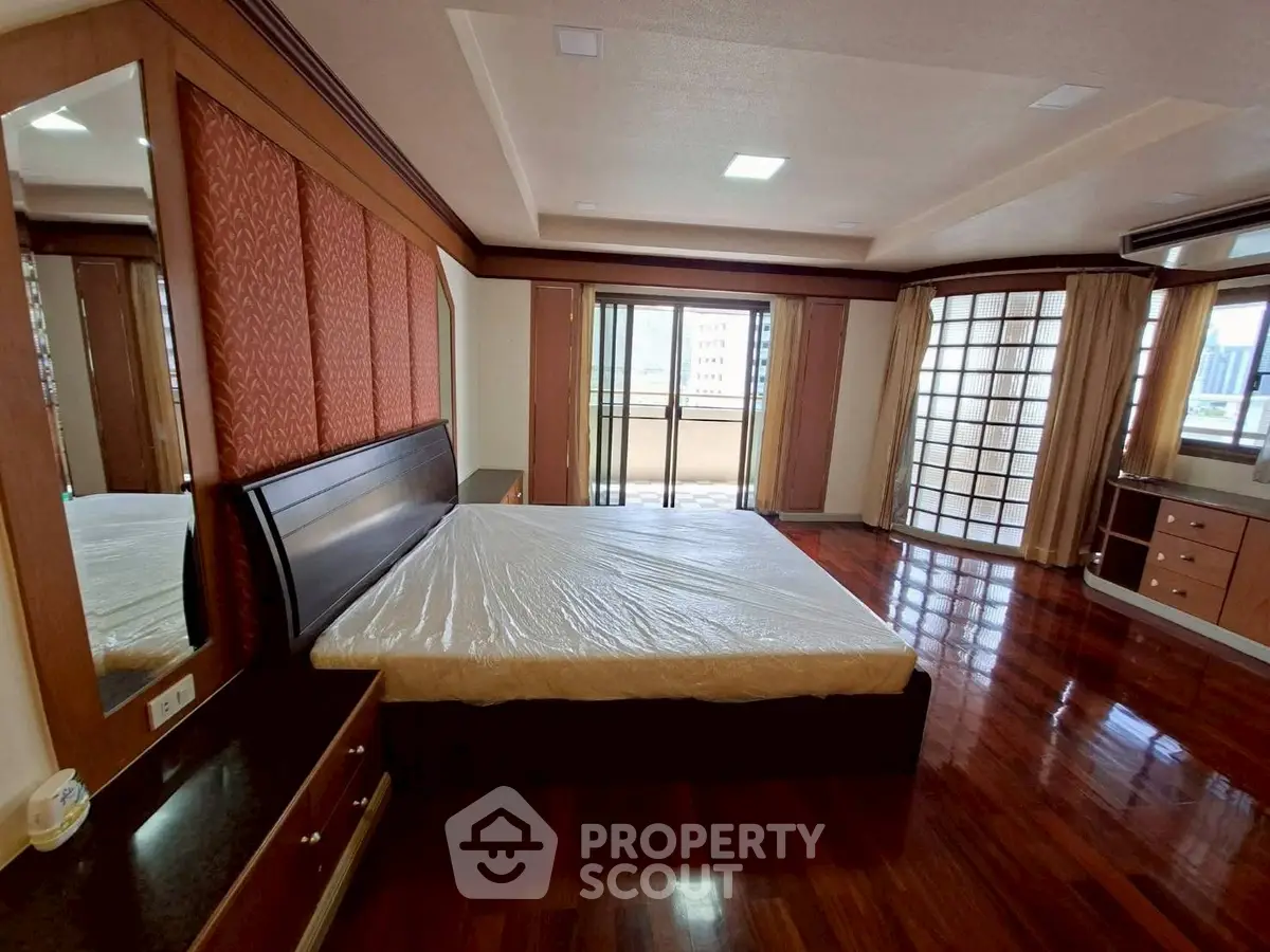 Spacious bedroom with hardwood floors and large windows offering natural light