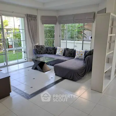 Spacious living room with large windows and garden view, featuring modern furniture and elegant decor.