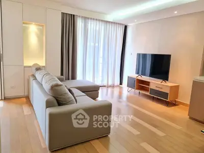 Spacious modern living room with sleek furniture and large TV, perfect for relaxation and entertainment.