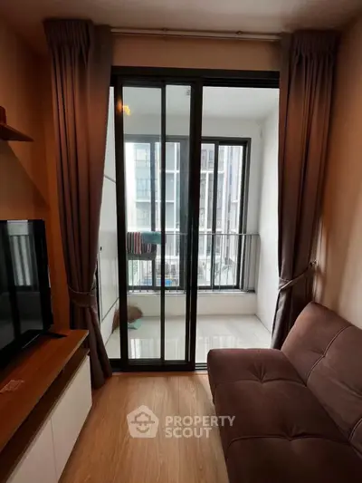 Modern living room with sliding glass doors leading to a small balcony in a high-rise apartment.