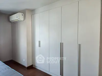 Spacious bedroom with sleek built-in wardrobe and modern air conditioning unit.