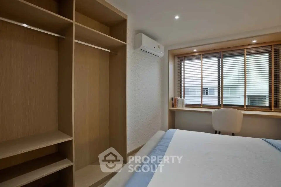 Modern bedroom with built-in wardrobe and large window for natural light.