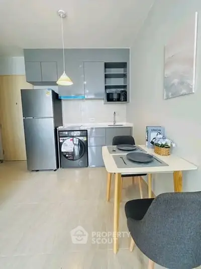 Modern kitchen with sleek appliances and cozy dining area in a stylish apartment.
