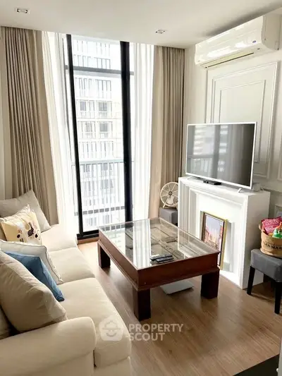 Modern living room with large windows, cozy sofa, and sleek TV setup in a stylish apartment.