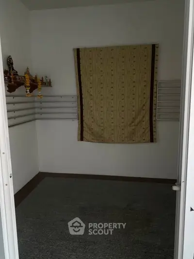 Cozy small room with wall-mounted shelves and a decorative curtain, ideal for storage or a compact study area.