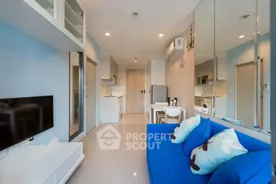 Modern living room with blue sofa and open kitchen layout in stylish apartment.