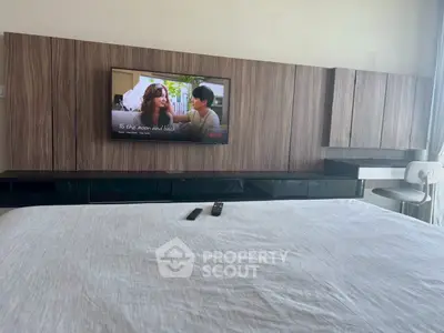 Modern bedroom with wall-mounted TV and sleek cabinetry design.