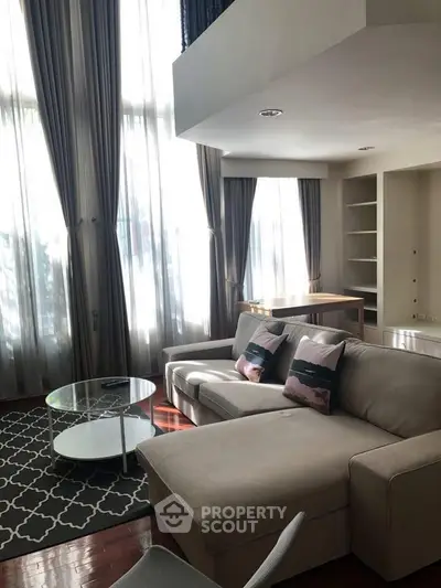Spacious living room with large windows and modern furniture in a stylish apartment.
