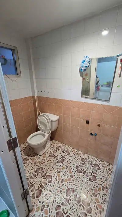 Cozy bathroom with tiled walls and floor, featuring a toilet and mirror.