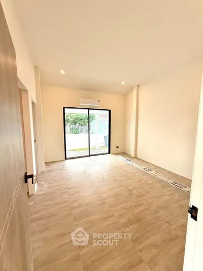Spacious empty room with large window and garden view, perfect for customization.