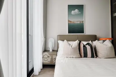 Modern bedroom with stylish decor and large window offering natural light.