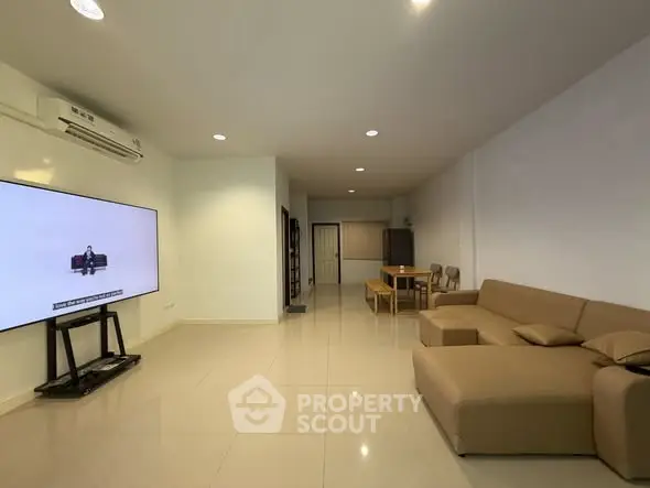 Spacious living room with modern furniture and large TV, perfect for relaxation.