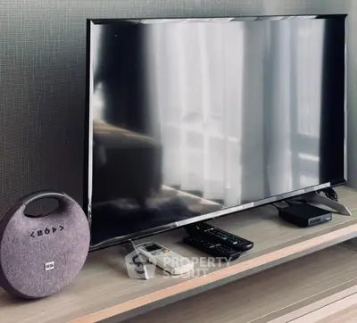 Modern living room setup with sleek TV and stylish accessories on wooden stand.