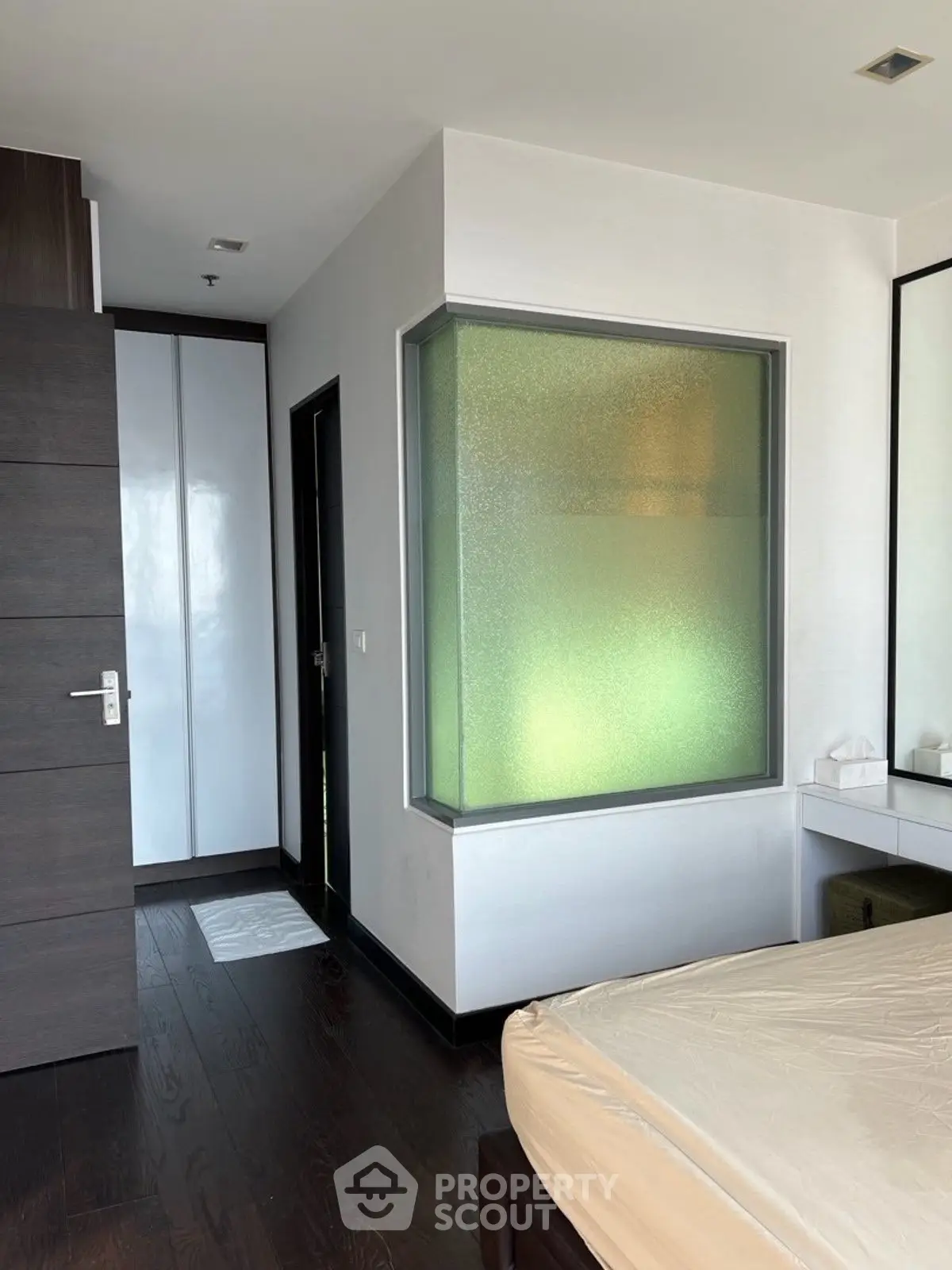Modern bedroom with frosted glass window and sleek wooden flooring