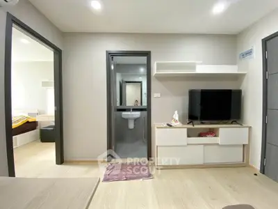 Modern apartment interior with TV and open layout, showcasing bedroom and bathroom access.